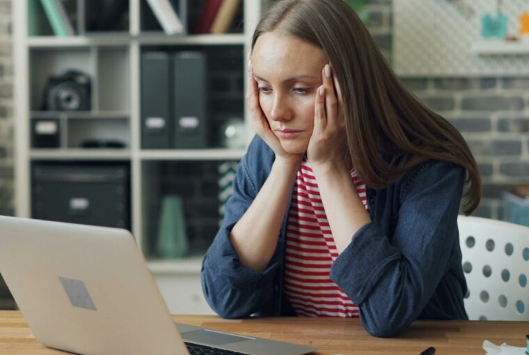 Mulher olha triste para o laptop