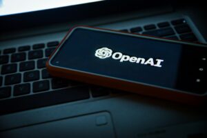 Teclado e smartphone com logomarca da OpenAI, empresa de IA generativa