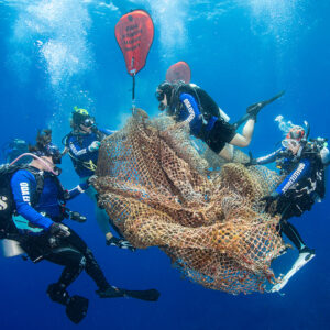 Voluntários removem rede de pesca abandonada no mar do Havaí, imagem vencedora do concurso de fotos do oceano da ONU em 2024