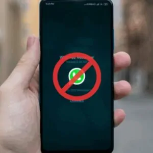 Mão segurando smartphone com o aplicativo WhatsApp e um sinal de proibido em vermelho sobre ele, simbolizando o possível bloqueio do WhatsApp na Rússia.