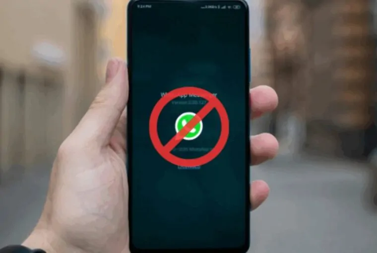 Mão segurando smartphone com o aplicativo WhatsApp e um sinal de proibido em vermelho sobre ele, simbolizando o possível bloqueio do WhatsApp na Rússia.