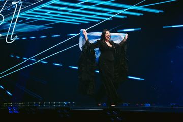 Cantora Yuval Raphael, de Israel, no Eurovision 2025, segurando bandeira do país 