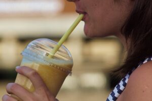 Jovem tomando milk-shake com food truck ao fundo