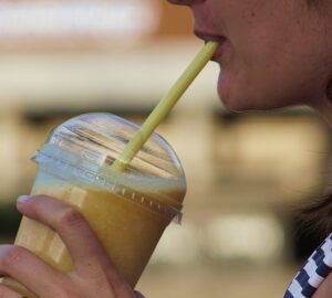 Jovem tomando milk-shake com food truck ao fundo