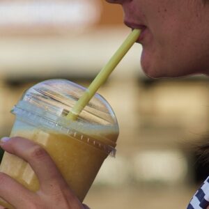 Jovem tomando milk-shake com food truck ao fundo