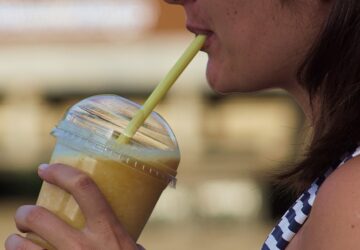 Jovem tomando milk-shake com food truck ao fundo