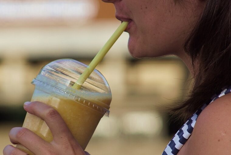 Jovem tomando milk-shake com food truck ao fundo