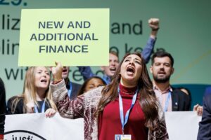 Manifestante pedindo compromissos por mais recursos para ação climática durante a COP29 em Baku