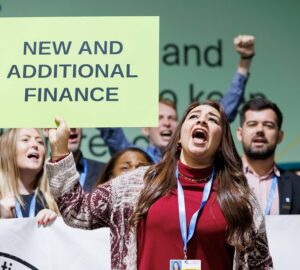 Manifestante pedindo compromissos por mais recursos para ação climática durante a COP29 em Baku