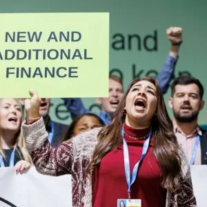Manifestante pedindo compromissos por mais recursos para ação climática durante a COP29 em Baku
