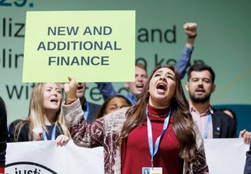Manifestante pedindo compromissos por mais recursos para ação climática durante a COP29 em Baku