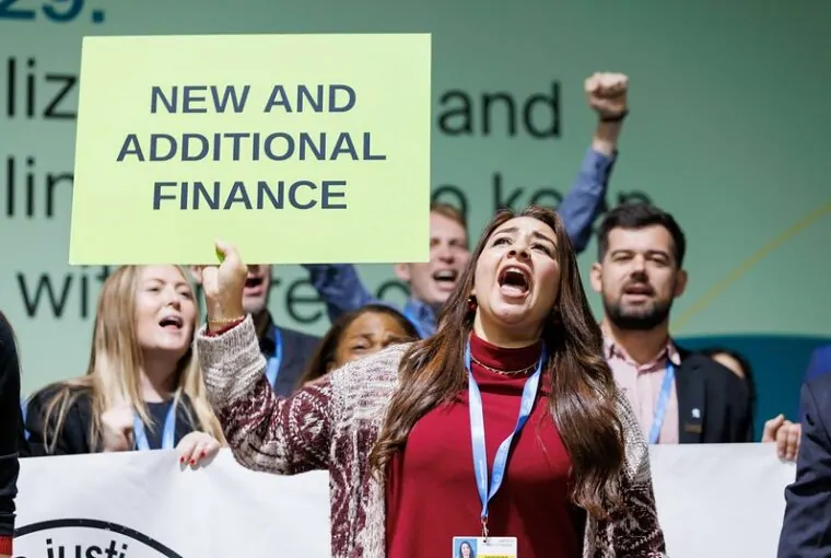 Manifestante pedindo compromissos por mais recursos para ação climática durante a COP29 em Baku