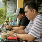 Homens com smartphone acessando internet em uma lanchonete