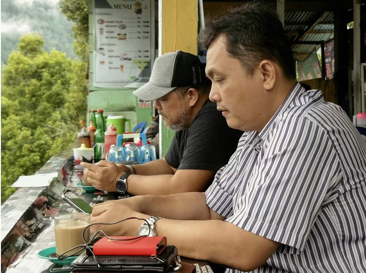 Homens com smartphone acessando internet em uma lanchonete