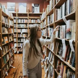 Mulher em biblioteca procurando livro