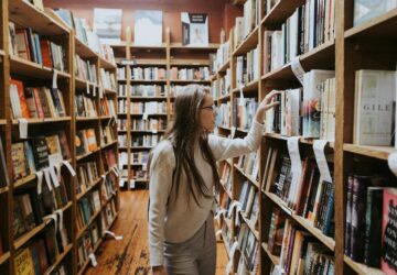 Mulher em biblioteca procurando livro