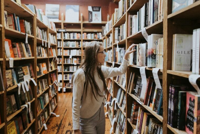 Mulher em biblioteca procurando livro