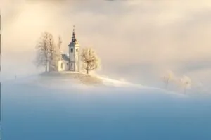 Igreja no alto da colina cercada e neve ao amanhecer. A foto foi uma das premiadas no concurso de fotografia colorida