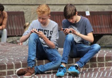 dois meninos lendo conteúdo no smartphone