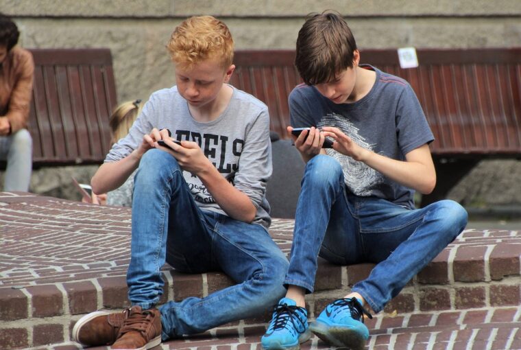 dois meninos lendo conteúdo no smartphone