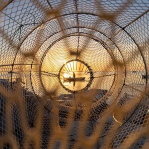 Um pescador em um barco foi retratado através de uma armadilha de pesca. A foto foi uma das vencedoras do concurso de fotografa de natureza da Wikipédia