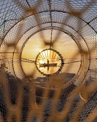 Um pescador em um barco foi retratado através de uma armadilha de pesca. A foto foi uma das vencedoras do concurso de fotografa de natureza da Wikipédia