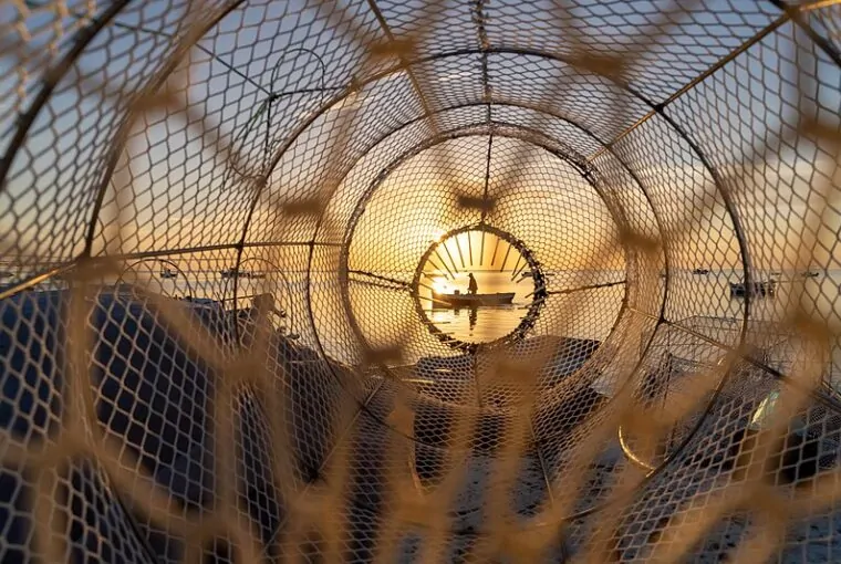 Um pescador em um barco foi retratado através de uma armadilha de pesca. A foto foi uma das vencedoras do concurso de fotografa de natureza da Wikipédia