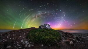 Um farol cercado pela Via Láctea, meteoros e luzes coloridas. A imagem foi premiada no concurso de fotos da aurora boreal