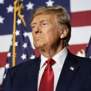 Donald Trump com bandeiras dos EUA ao fundo