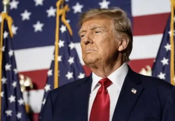 Donald Trump com bandeiras dos EUA ao fundo