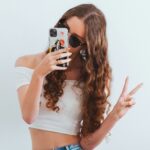 Menina adolescente com smartphone fazendo sinal positivo