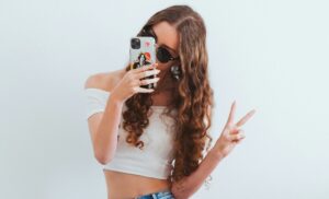 Menina adolescente com smartphone fazendo sinal positivo
