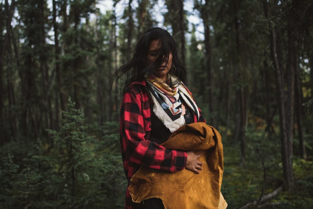 Mulher com roupas coloridas diante de floresta