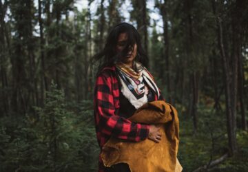 Mulher com roupas coloridas diante de floresta