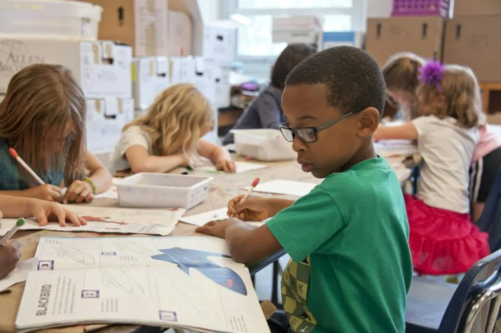 Crianças desenhando em mesa de escola