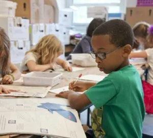 Crianças desenhando em mesa de escola