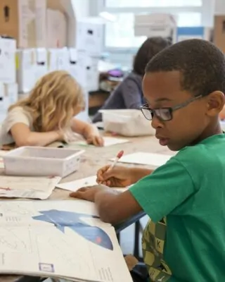 Crianças desenhando em mesa de escola