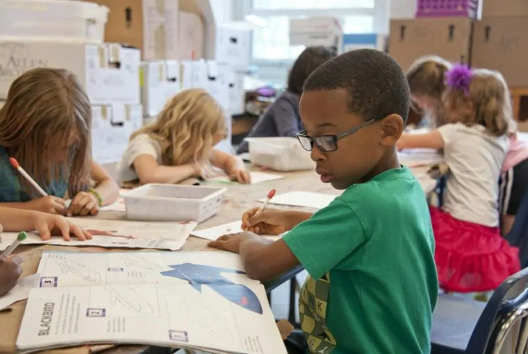 Crianças desenhando em mesa de escola