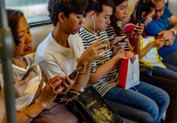pessoas no metrô lendo no smartphone, usado cada vez mais para consumo de notícias nas redes sociais