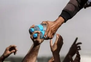 Mãos esticadas pegando garrafas de água em Gaza, foi uma das finalistas do concurso de fotografia de tempestade