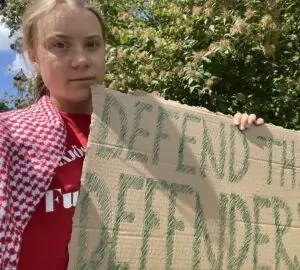 Greta Thumberg, ativista ambiental, segurando cartaz contra violência voltada a ativistas ambientais