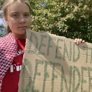Greta Thumberg, ativista ambiental, segurando cartaz contra violência voltada a ativistas ambientais
