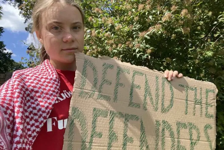Greta Thumberg, ativista ambiental, segurando cartaz contra violência voltada a ativistas ambientais