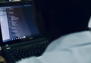 Homem no computador com tela exibindo códigos