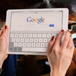 Mãos segurando um tablet com a página de busca do Google aberta, ilustrando o contexto da queixa antitruste contra o Google por uso de IA nos resultados de busca