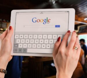 Mãos segurando um tablet com a página de busca do Google aberta, ilustrando o contexto da queixa antitruste contra o Google por uso de IA nos resultados de busca