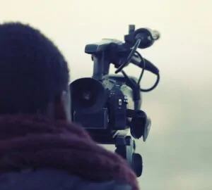 cinegrafista negro de costas atrás de uma câmera