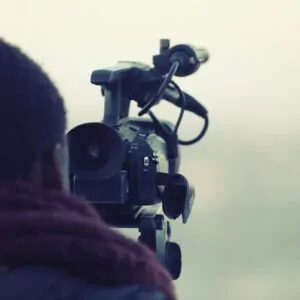 cinegrafista negro de costas atrás de uma câmera