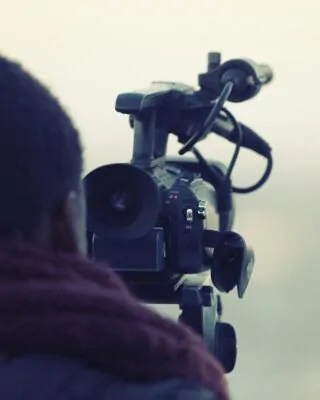 cinegrafista negro de costas atrás de uma câmera