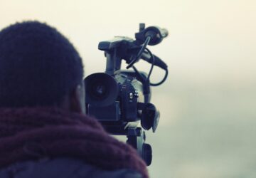 cinegrafista negro de costas atrás de uma câmera